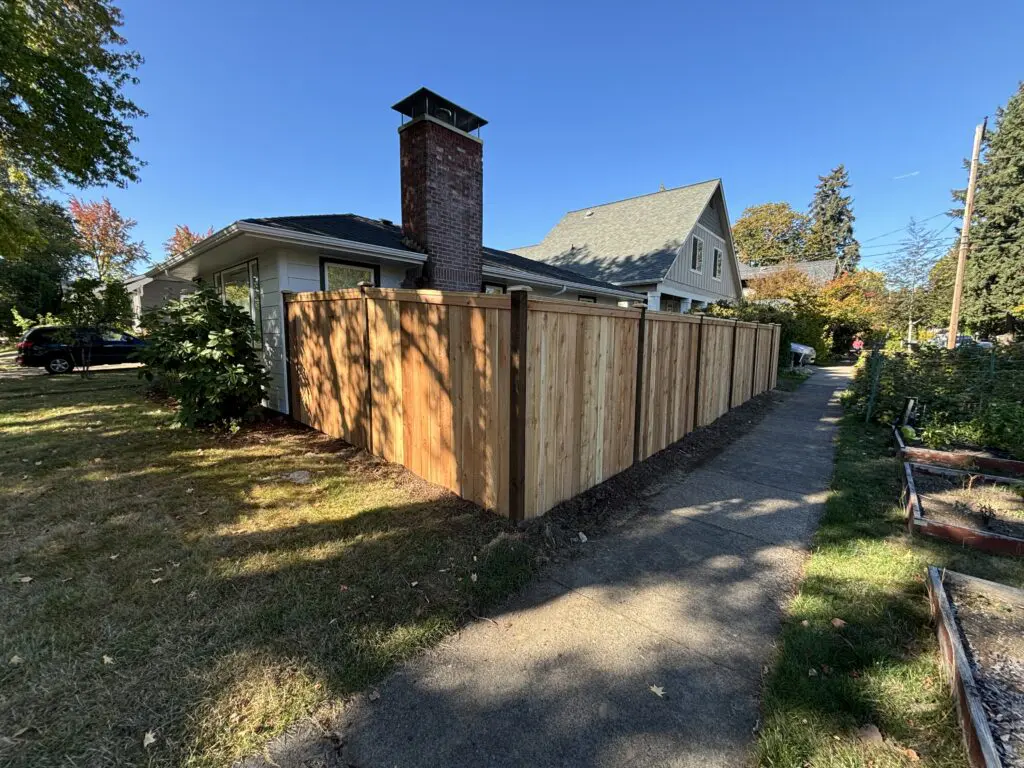 Newly installed cedar privacy fence surrounding a residential property with clear blue sky, showcasing Timberhill Fence & Deck's quality craftsmanship in outdoor wood fencing and deck services.